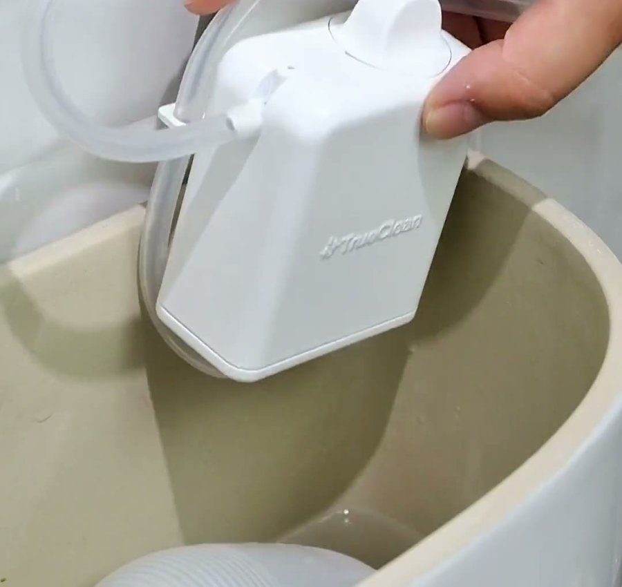 The dispenser hanging inside the tank, clip bent over the edge